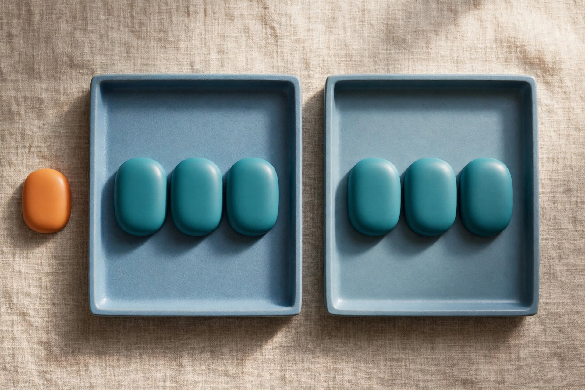 Two blue trays hold rows of teal tokens, with an orange token placed beside one tray on a textured surface.