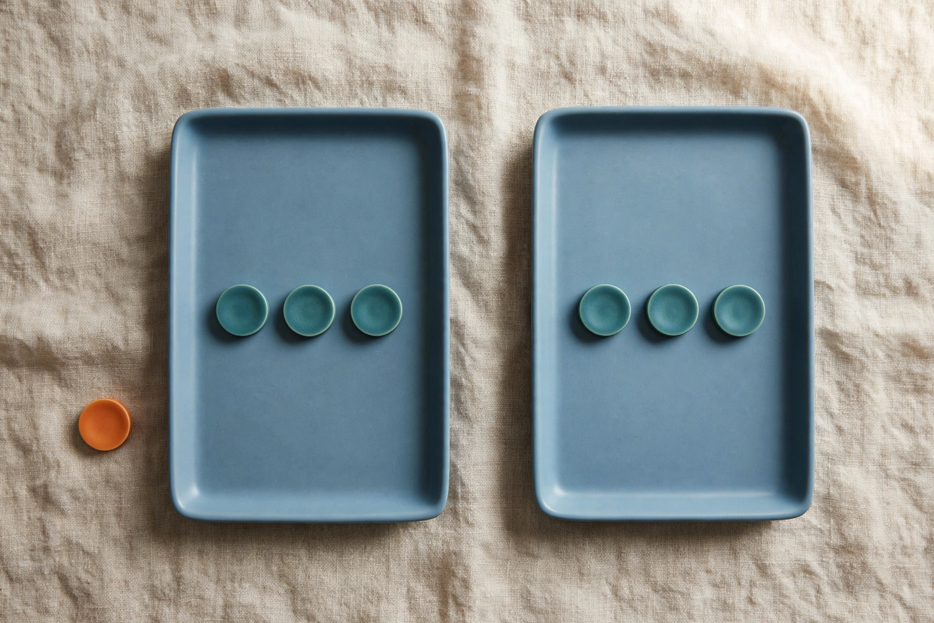 Two blue trays each hold three teal tokens, with an orange token placed beside the left tray.