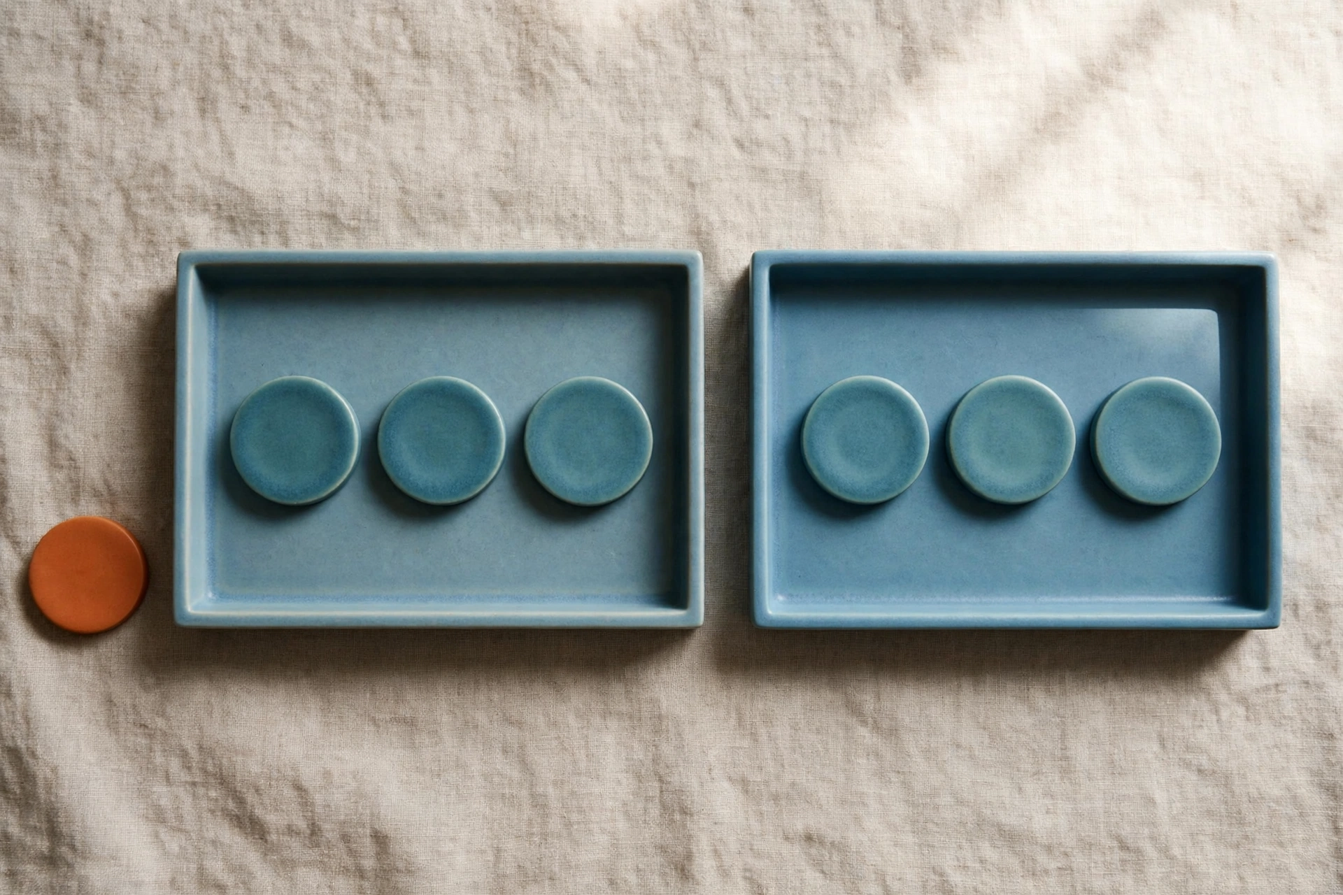 Two blue trays each hold three teal tokens, with an orange token placed beside the left tray.