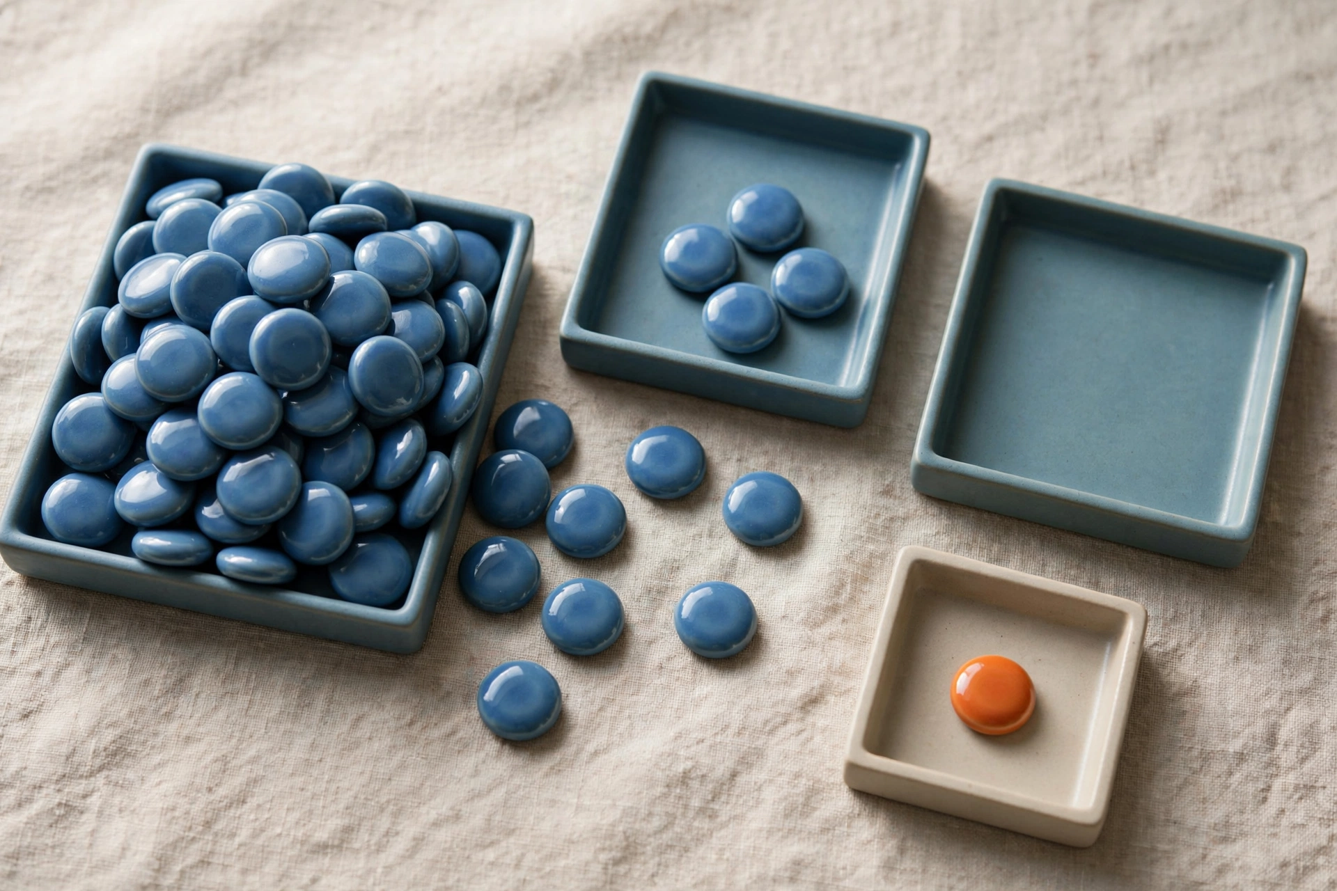 Blue ceramic tokens are distributed among three trays, with an orange token isolated in a separate tray.