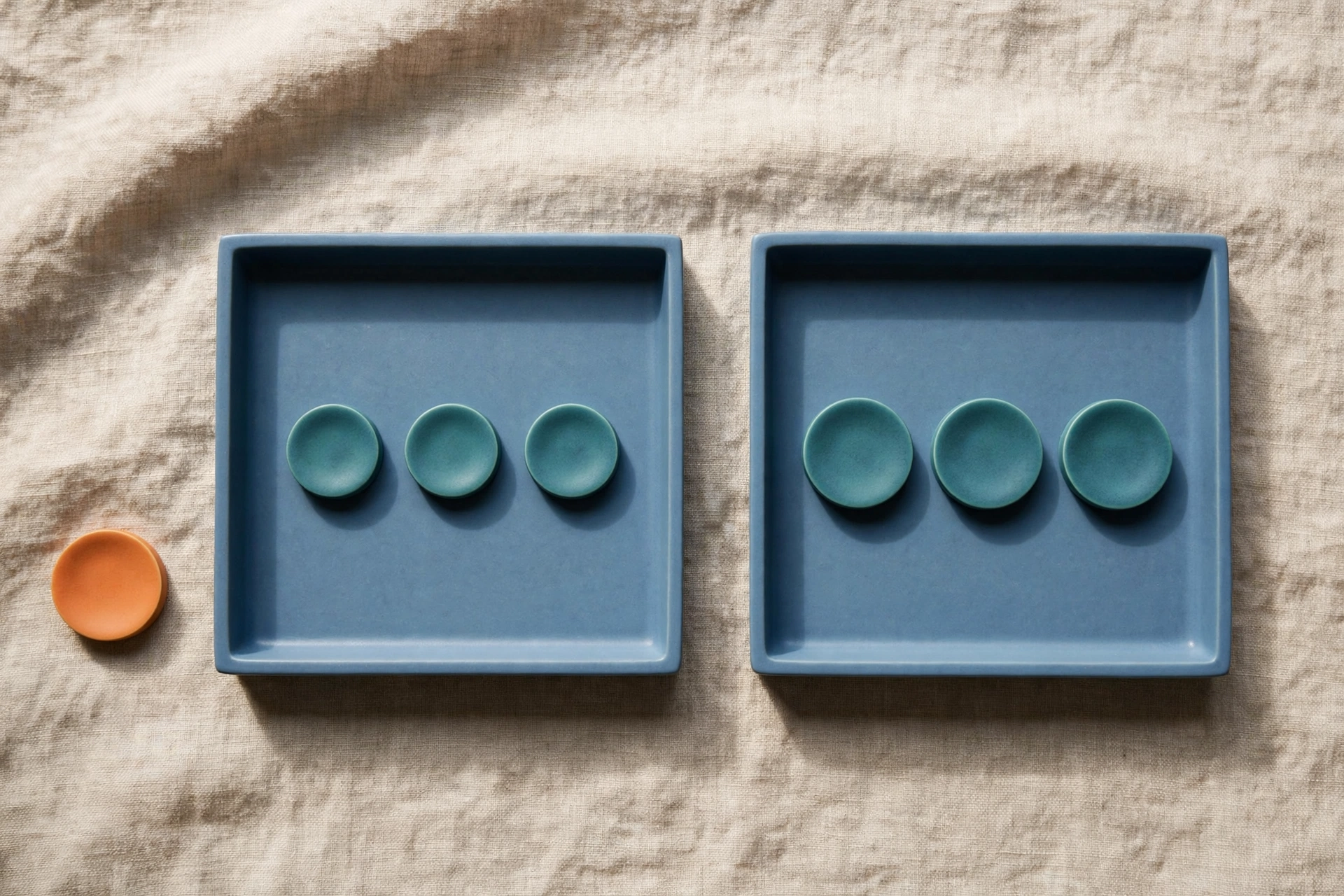 Two blue trays each hold three teal tokens, with an orange token placed beside the left tray.