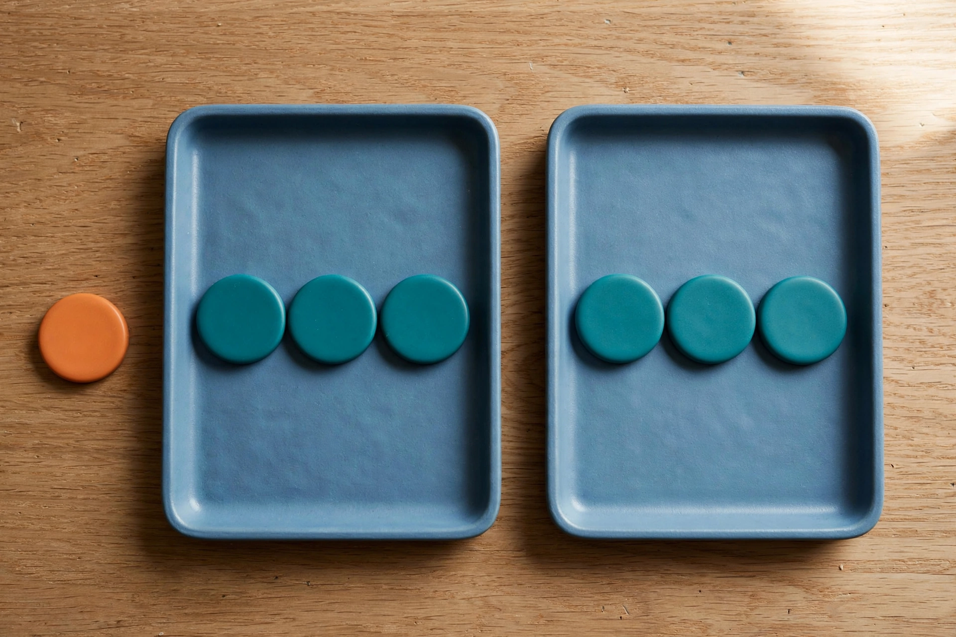 Two blue trays with teal tokens sit on a wooden surface next to an orange token, representing a billing metaphor.