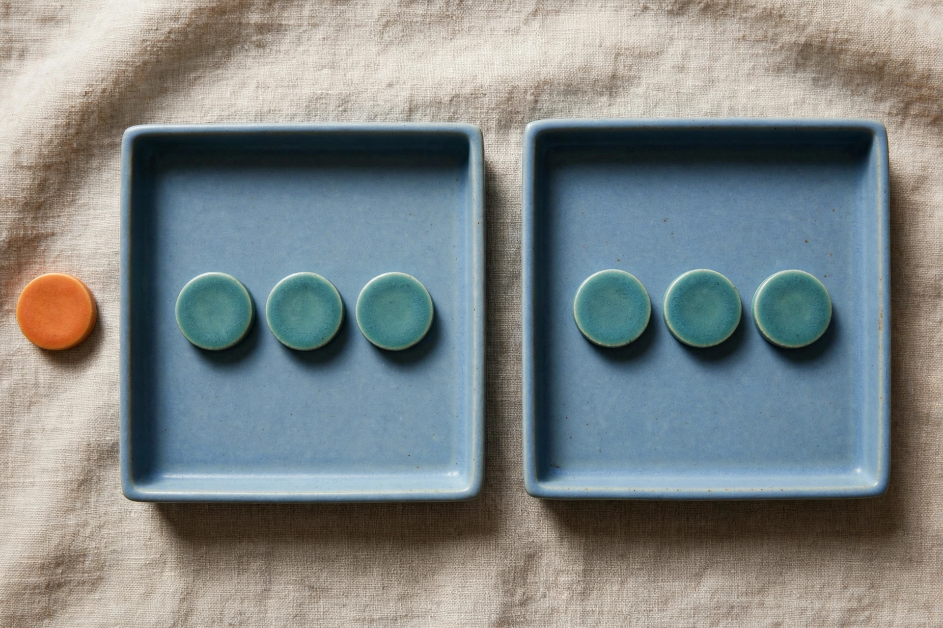 Two blue trays each hold three teal tokens, with an orange token placed beside the left tray.