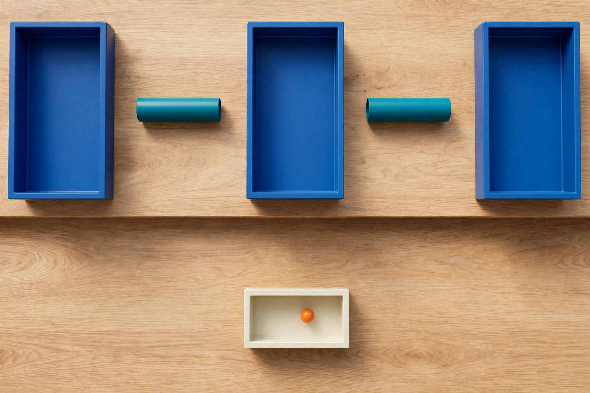 Three blue rectangular trays are arranged on a wooden surface, with two teal cylinders placed between them.