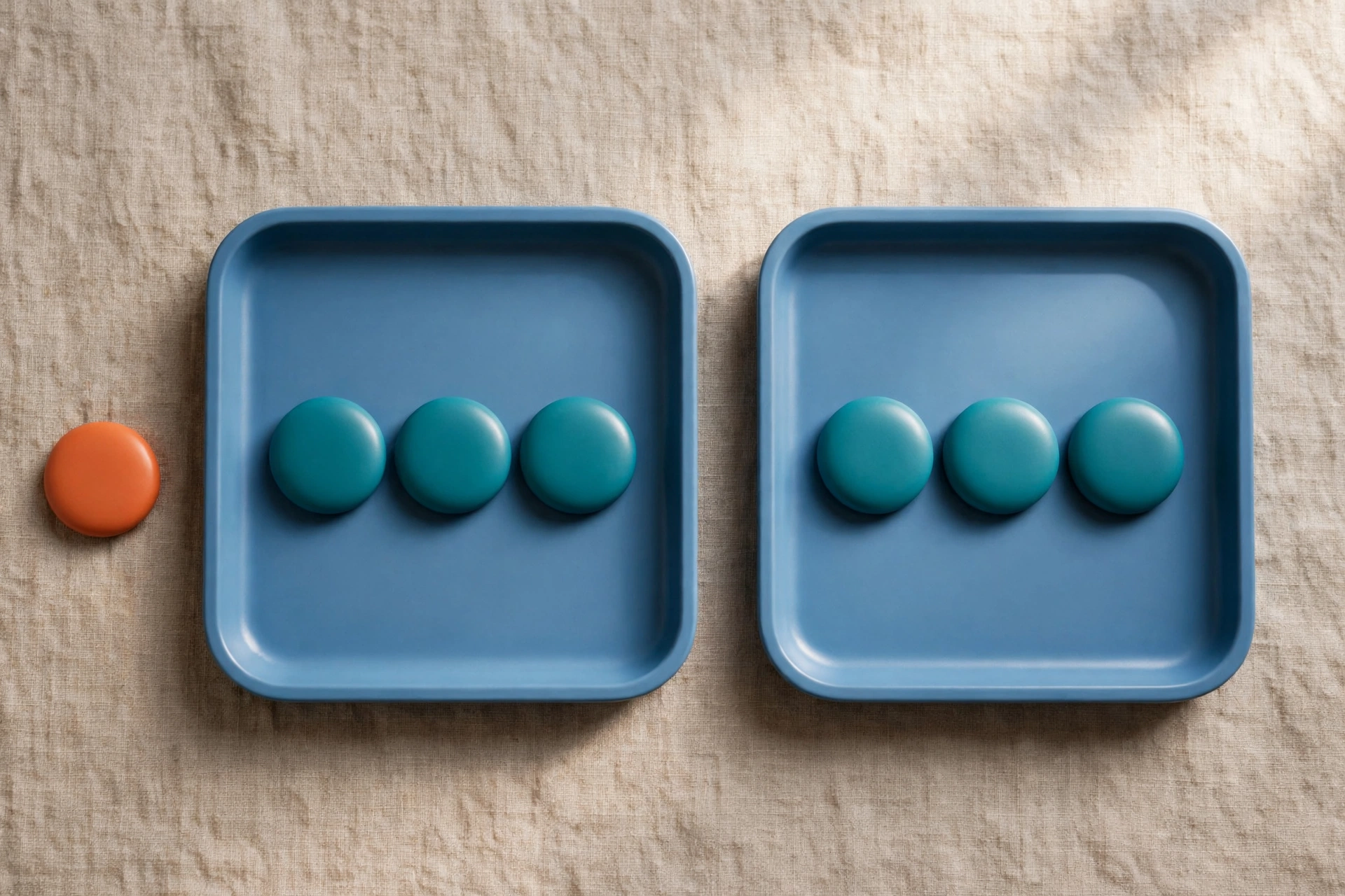Two blue trays hold rows of teal tokens, with an orange token placed beside one tray on a textured surface.
