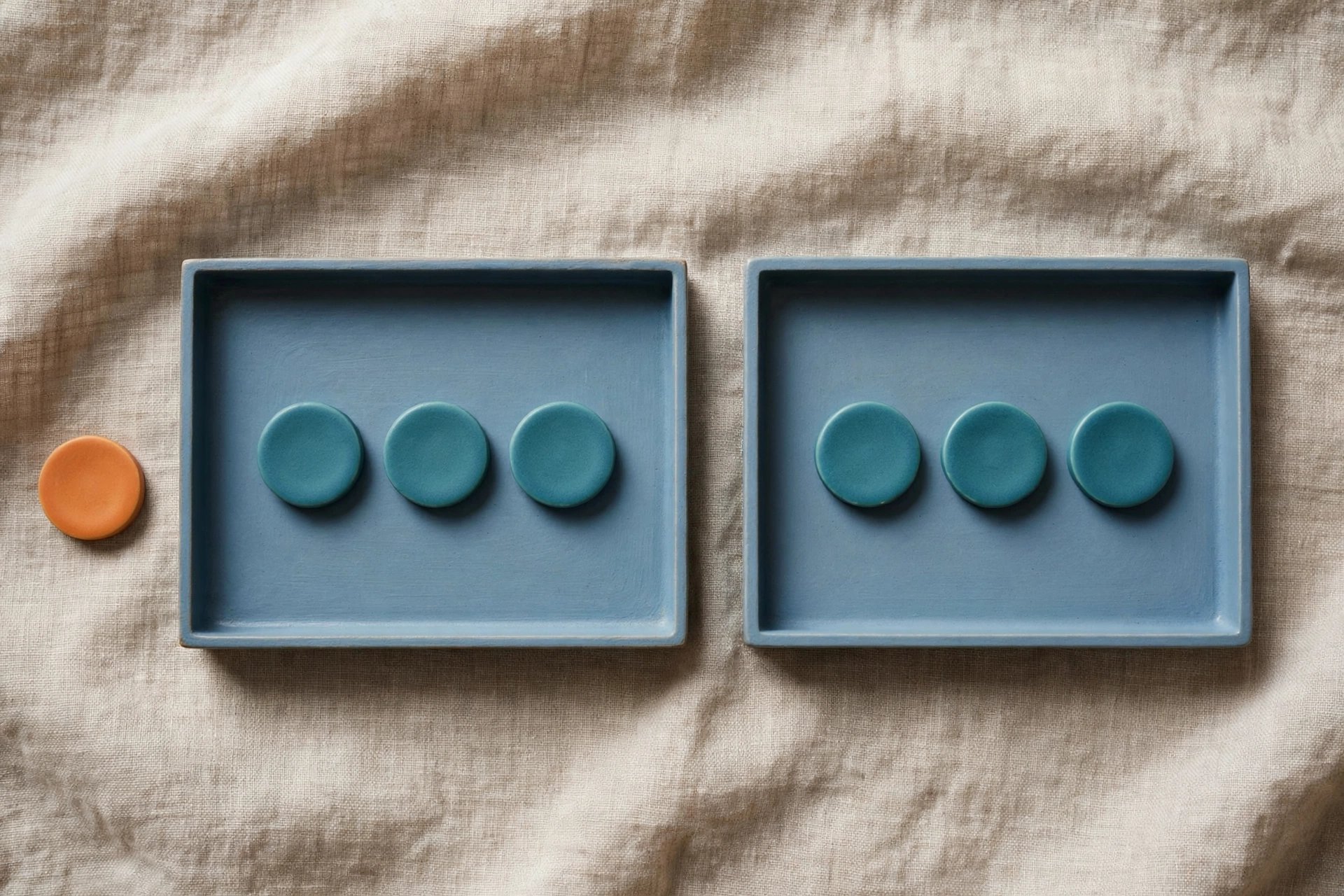 Two blue trays each hold three teal tokens, with an orange token placed beside the left tray.