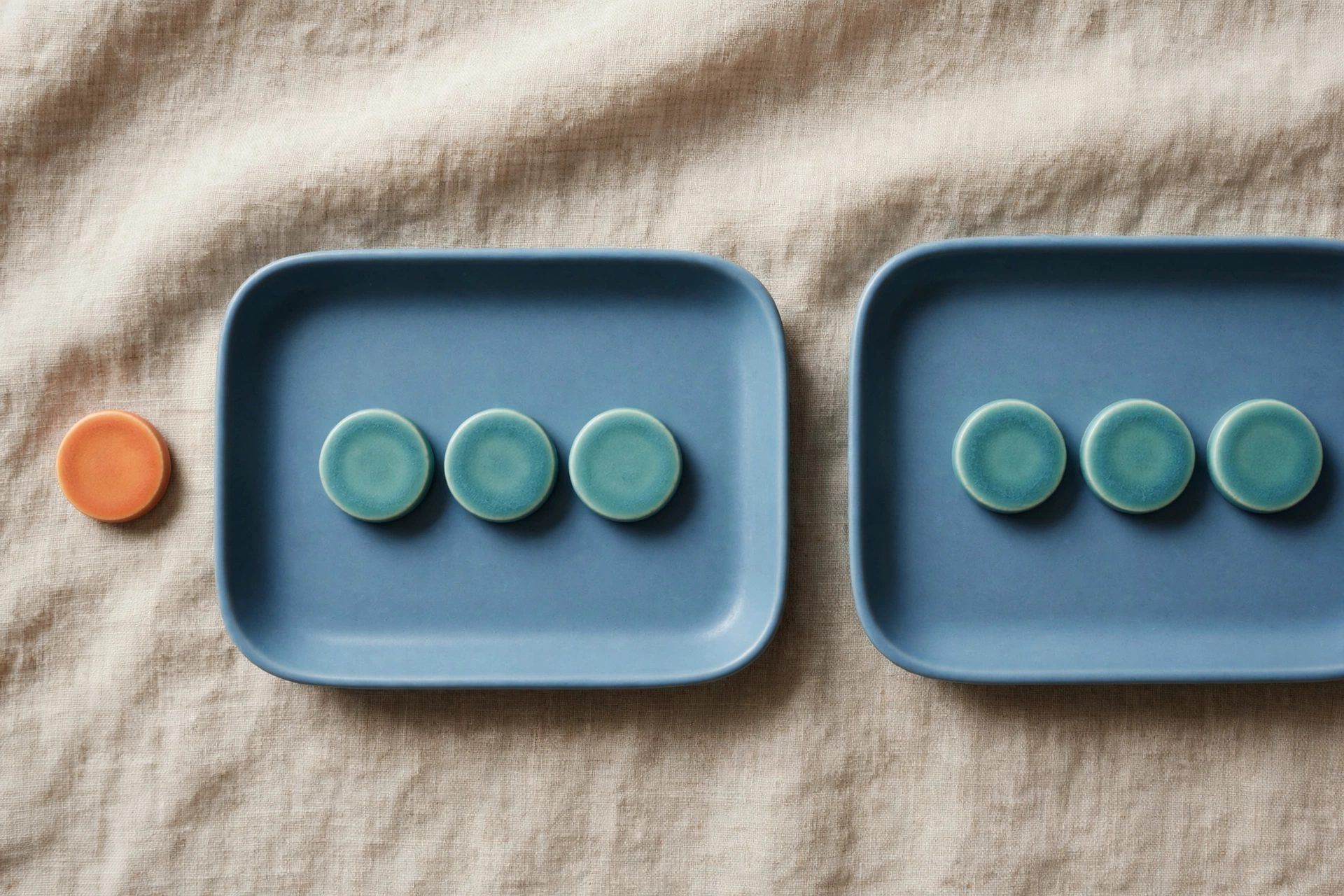 Two blue trays each hold three teal tokens, with one orange token placed beside the left tray.