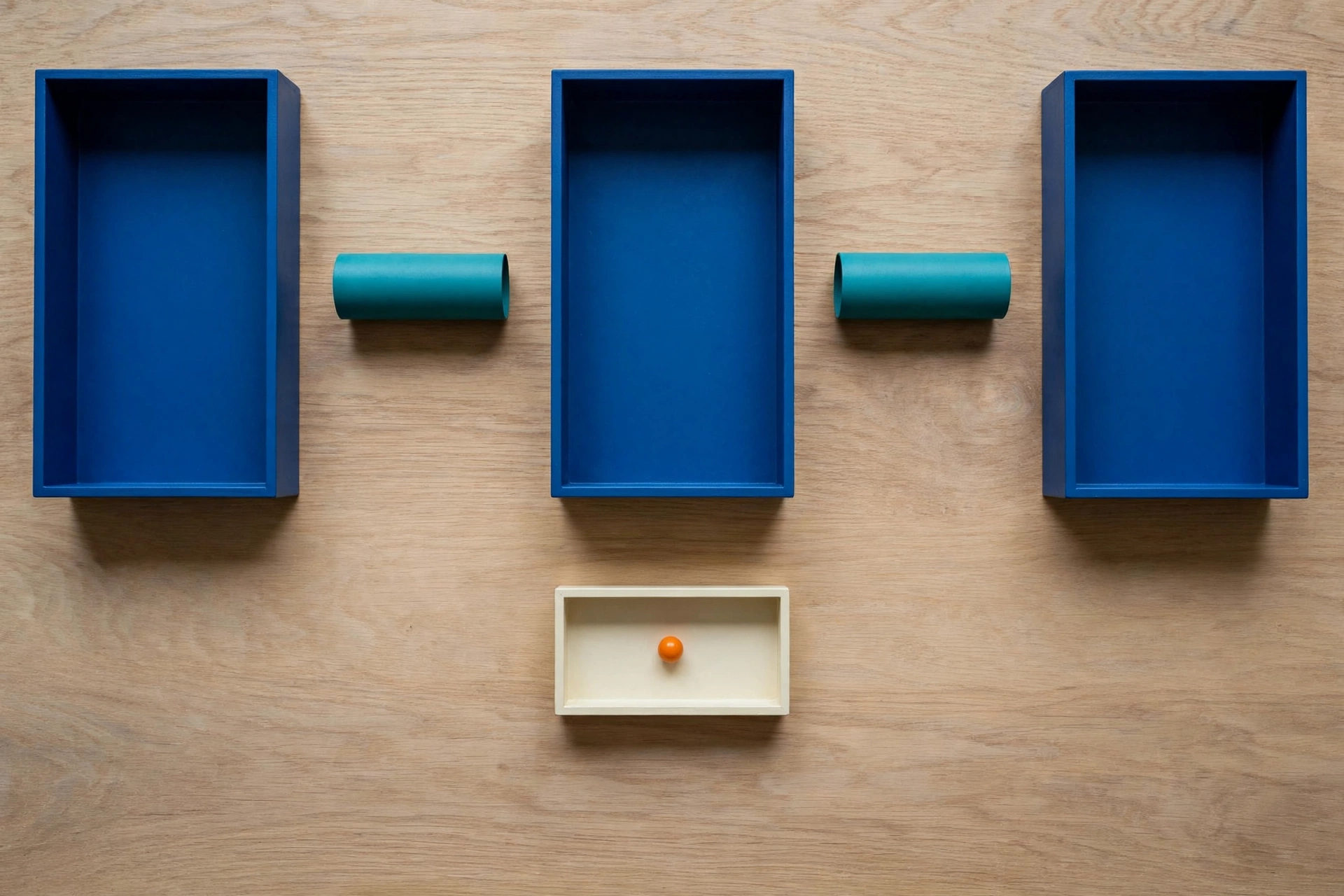 Three blue rectangular trays are arranged in a row on a wooden surface, with teal cylinders in the gaps between them.
