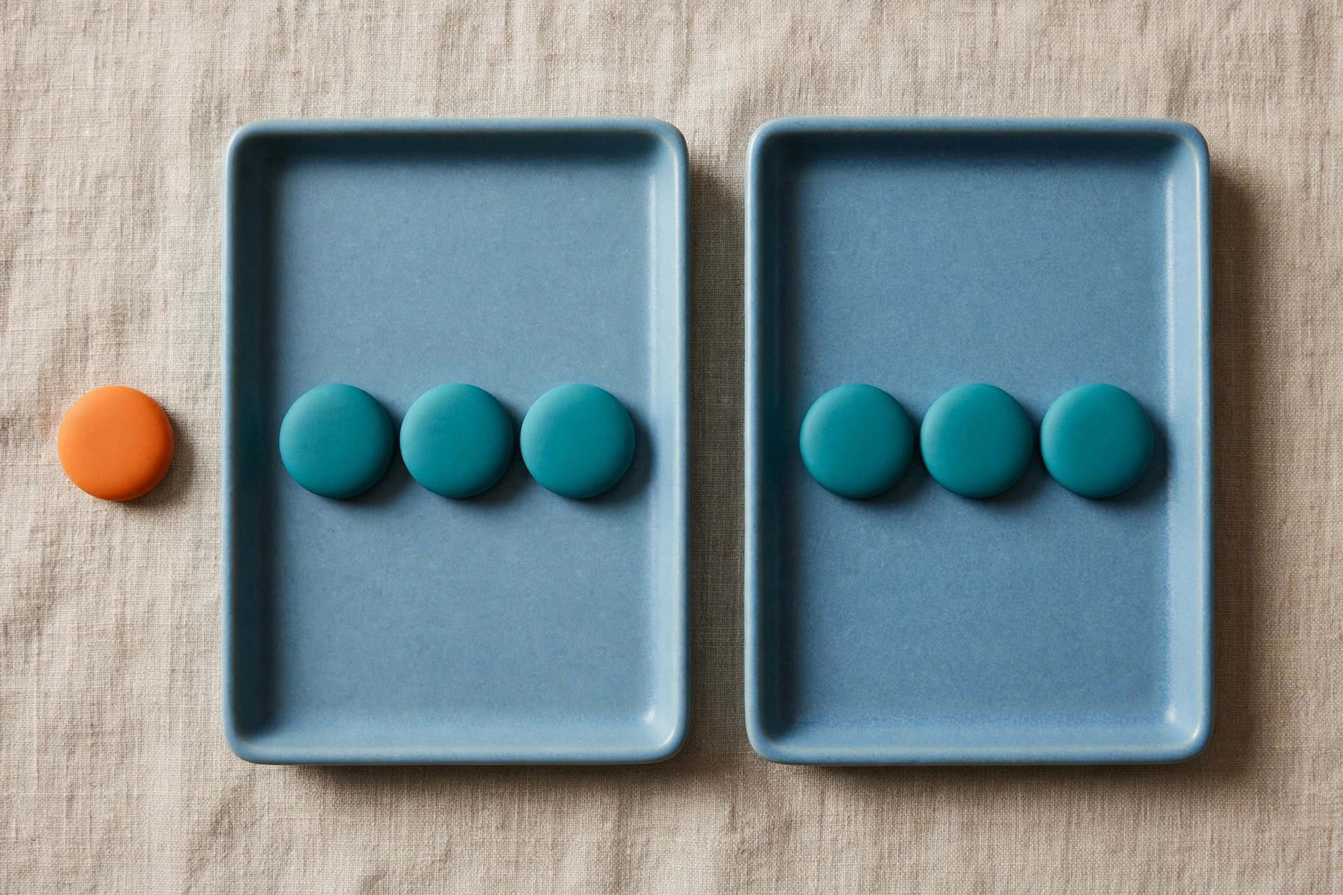 Two blue trays with teal tokens sit side by side, with an orange token placed separately to the left.