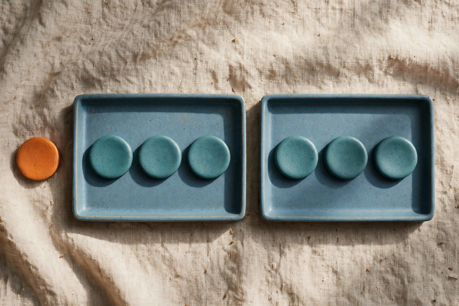Two blue trays each hold three teal tokens, with an orange token placed beside the left tray.