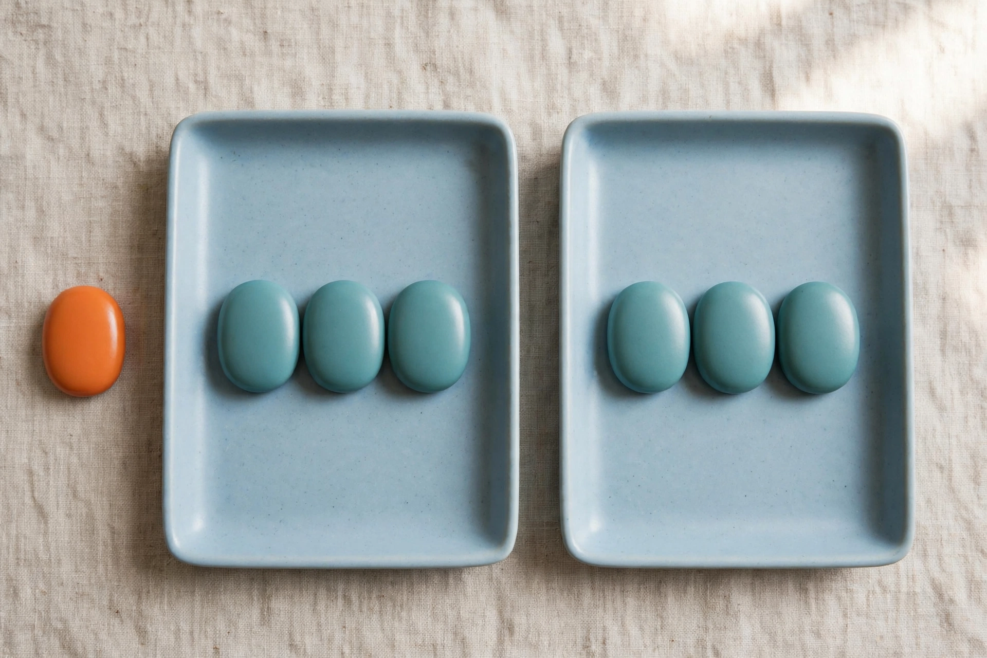 Two blue trays each hold three teal tokens, with an orange token placed beside the left tray.