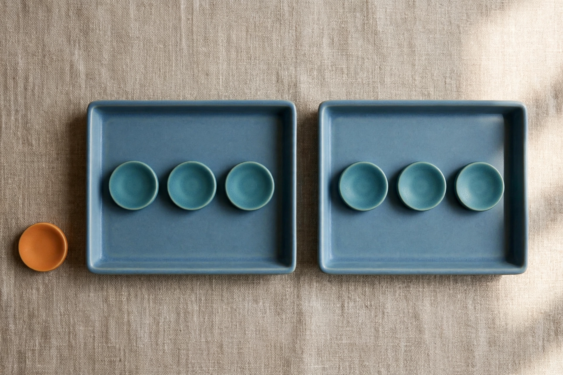 Two blue trays each hold three teal tokens, with one orange token placed beside a tray.
