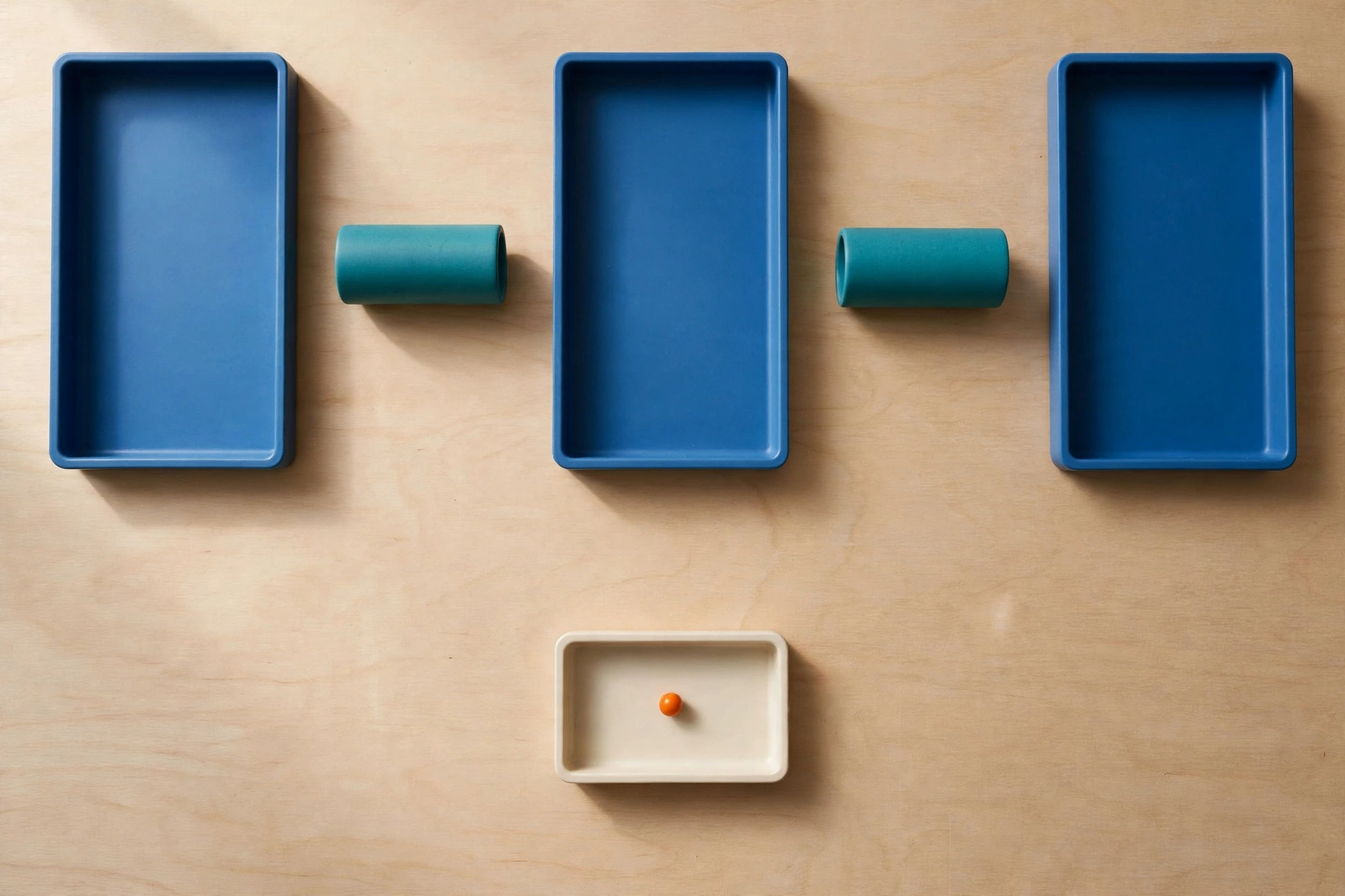 Three blue rectangular trays are arranged horizontally with two teal cylinders between them on a wooden surface.