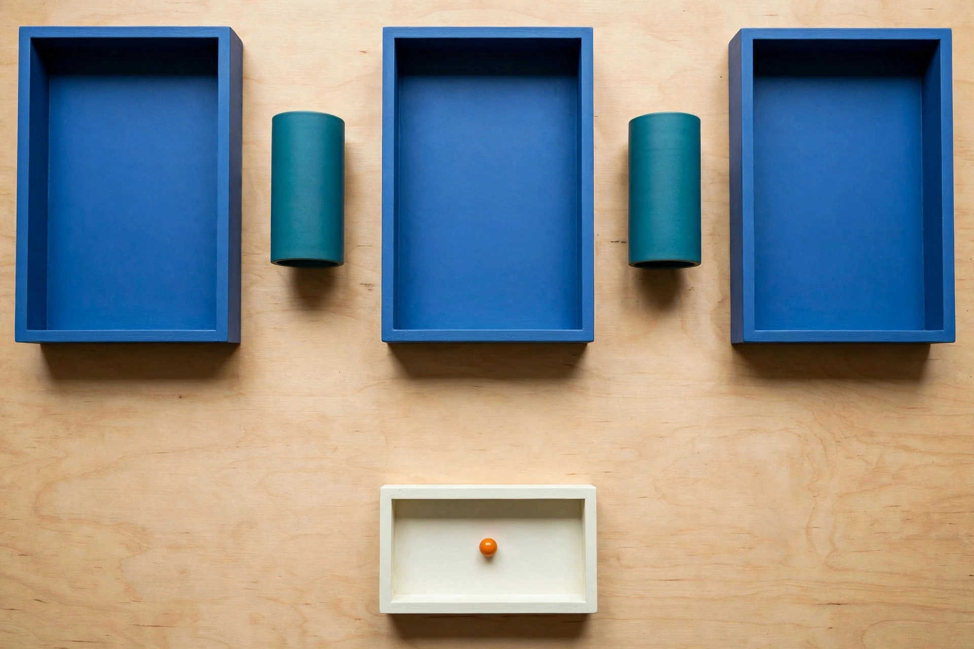 Three blue rectangular trays are arranged horizontally above a single ivory rectangular tray containing an orange bead.