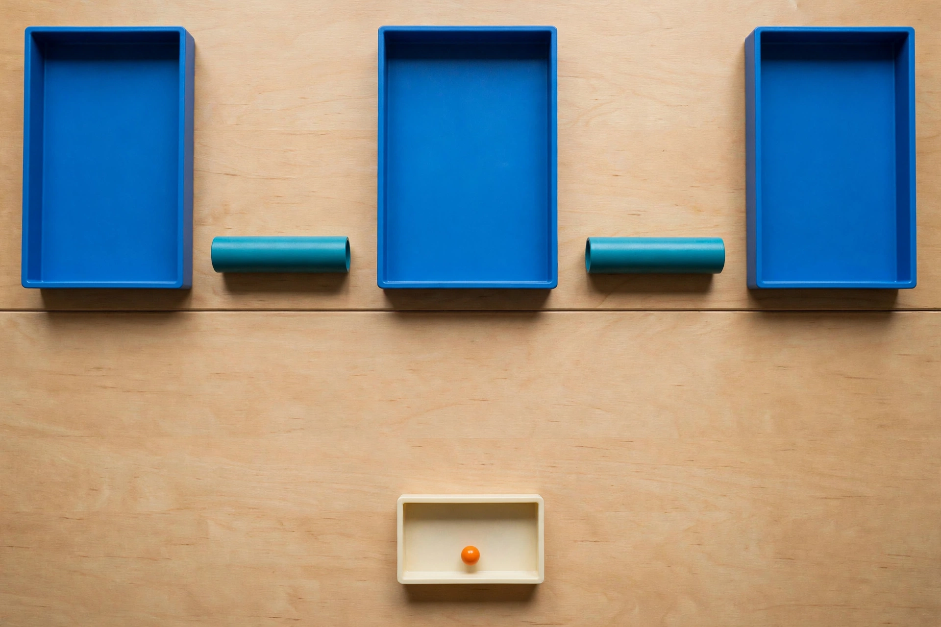 Three blue rectangular trays are arranged in a row on a wooden surface, with teal cylinders in the gaps between them.